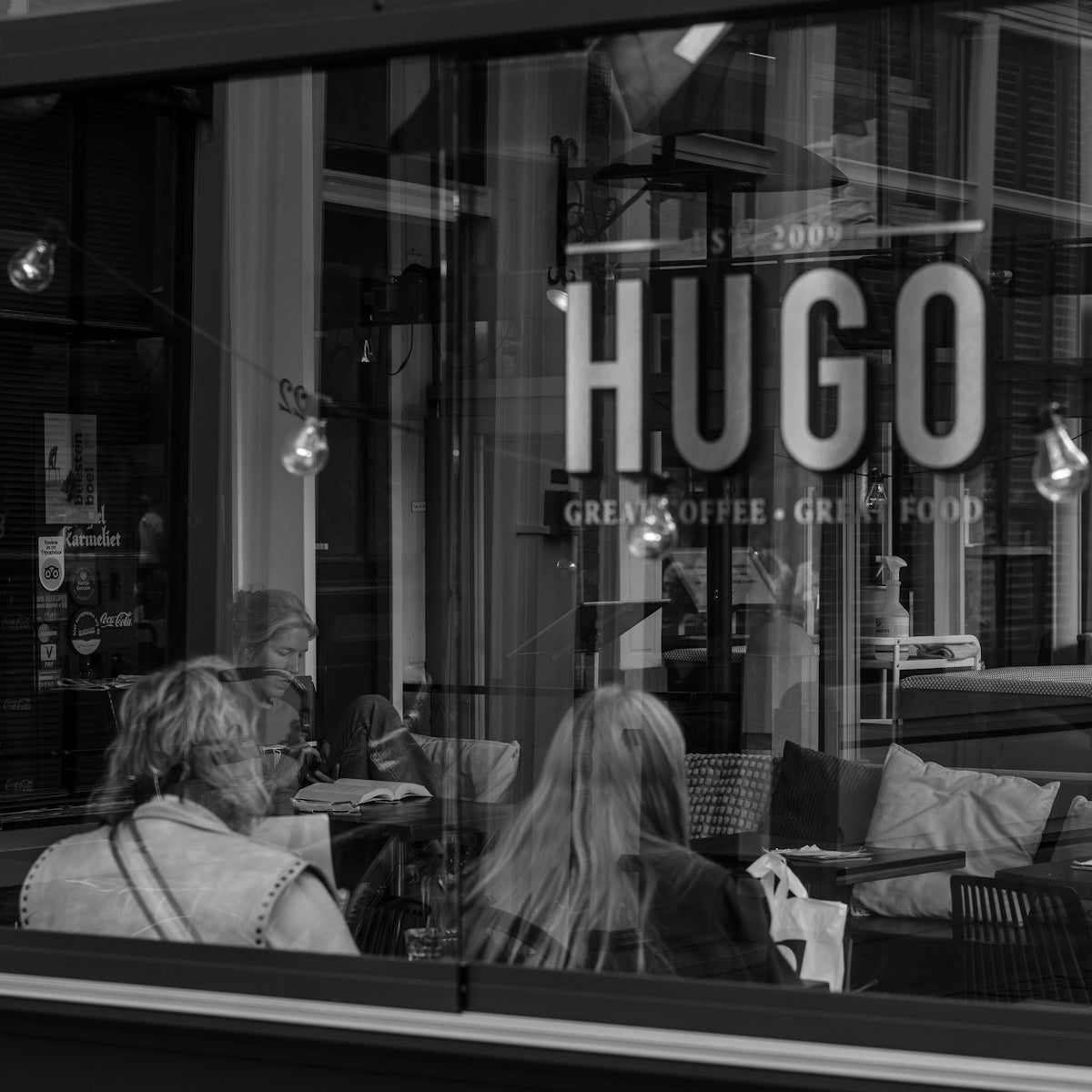 People sitting inside a cafe with hugo sign