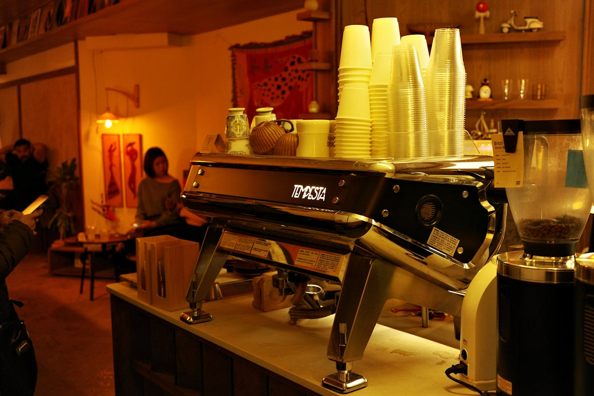 Shiny espresso machine with stacked cups in cafe